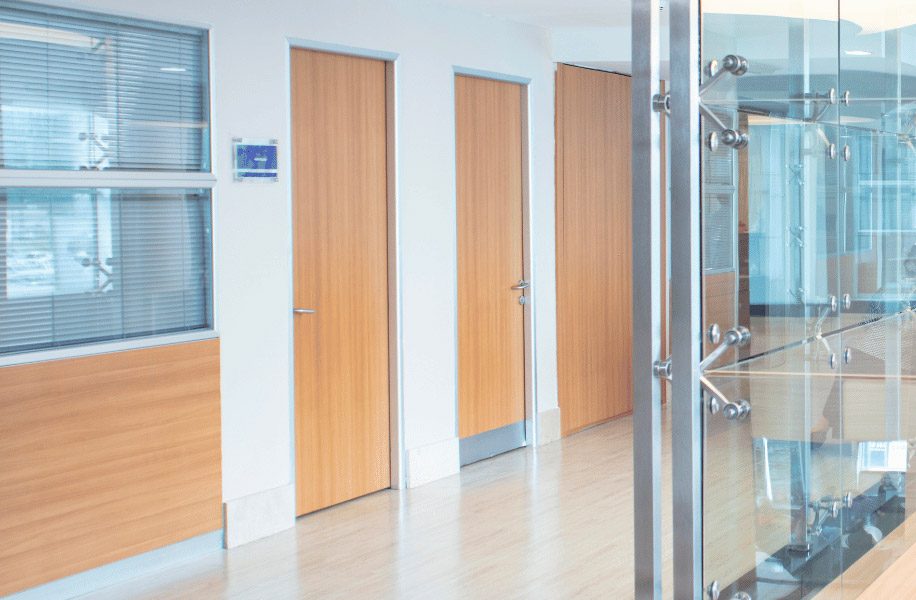 Light wood doors in a modern office hallway with glass partitions