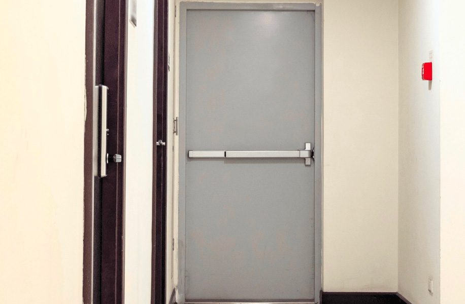 Porte coupe-feu grise avec barre anti-panique dans un couloir de bâtiment