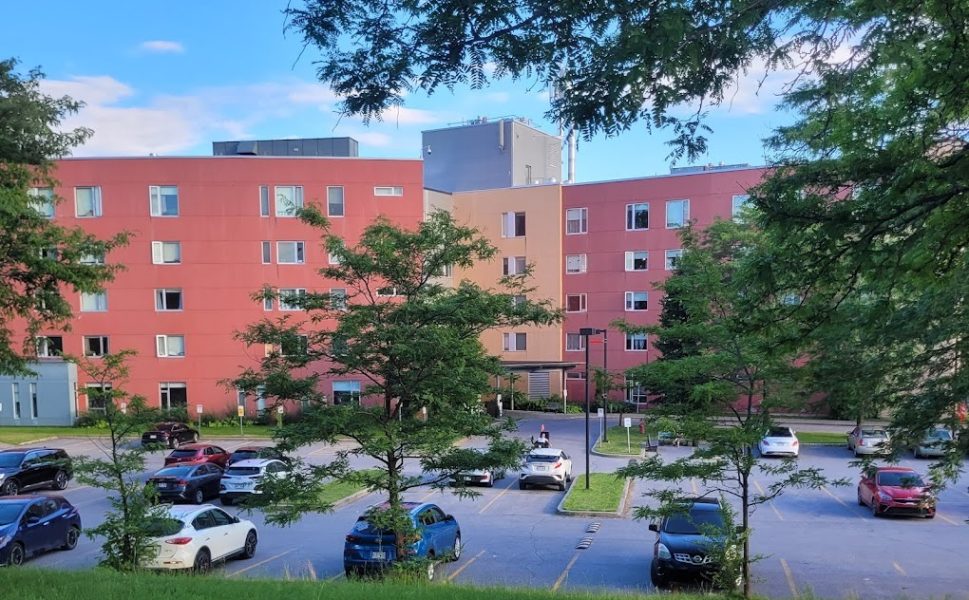 Cité-de-la-Santé residence in Laval with red facade and parking lot surrounded by trees