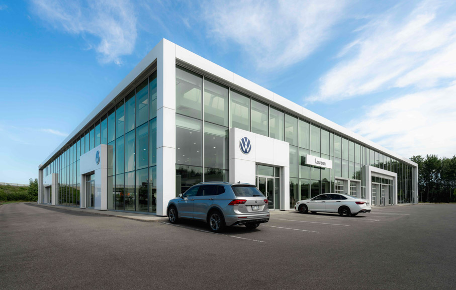 Volkswagen Louzon dealership in Laval with modern glass architecture and cars parked at the entrance