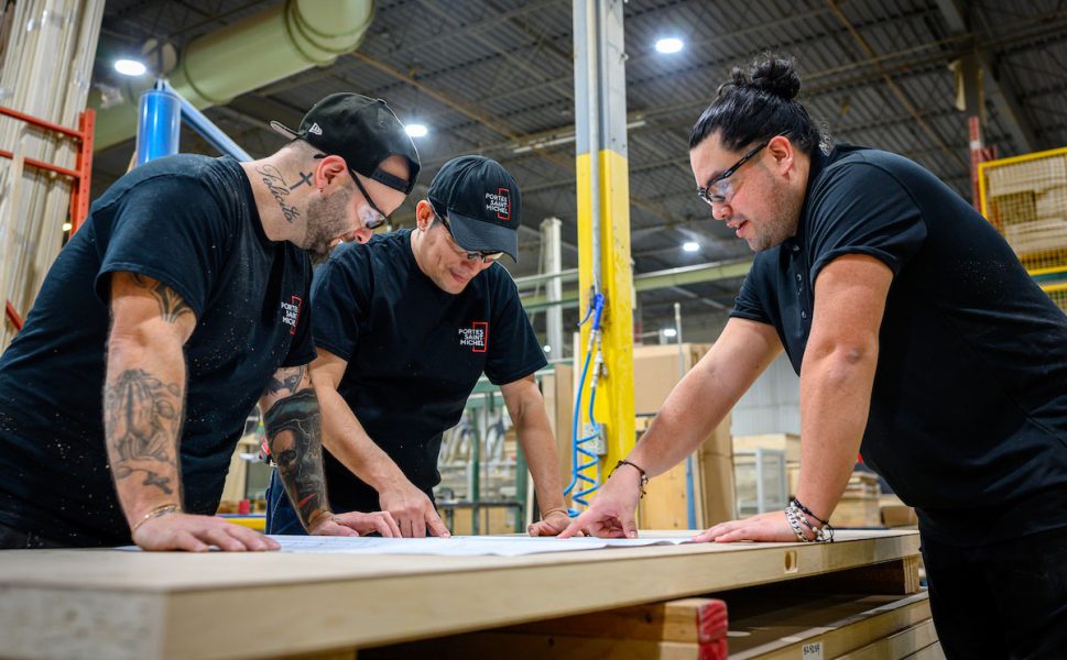 Portes Saint-Michel production team working on door manufacturing plans in the factory